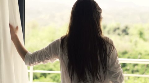 Young woman unveil curtain, walking out on terrace, slow motion shot at 240fps
