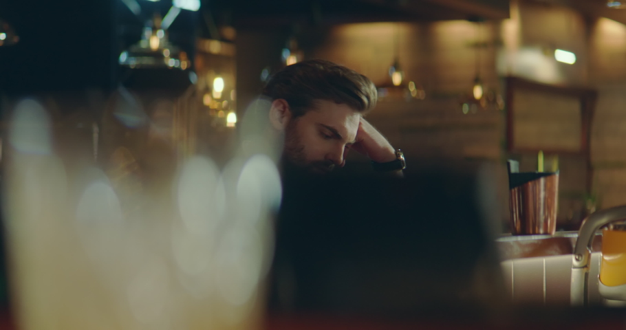 Portrait of handsome 30s adult Caucasian male enjoying a drink at the bar or restaurant in the evening. Shot with 2x anamorphic lens Royalty-Free Stock Footage #1090546113