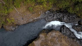 Aerial overhead footage of river flowing through rocky terrain in the forest.