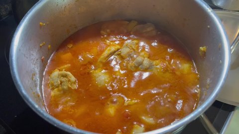 A pot of Romanian chicken paprikash bubbling on a stove