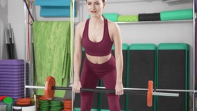 a beautiful and slender young woman does exercises with dumbbells in the gym. video and online lessons for sports. clothes and shoes for gymnastics. professional fitness trainer.