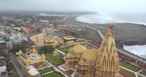 somnath , Gujarat , India - 05 20 2022: Aerial drone rotating view of Somnath temple with city houses view. SOMNATH TEMPLE, GUJARAT. Aerial view of oldest jyotherling of INDIA Somnath Mahadev Mandir.