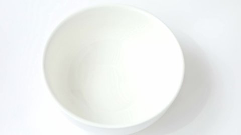 cornflakes fall into a white cup on a light background