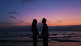 Beautiful Silhouette of Romantic Young Couple Kissing on the Beach in Hawaii at Dusk