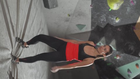 Vertical video, portrait of a female climber stands against the background of a climbing wall and use magnesia before climbing.