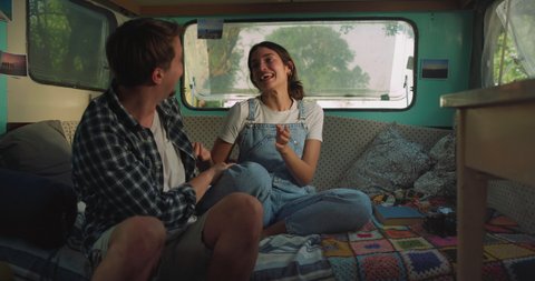 Cinematic shot of carefree couple in love having fun inside their trailer while enjoying together romantic trip with camping caravan.