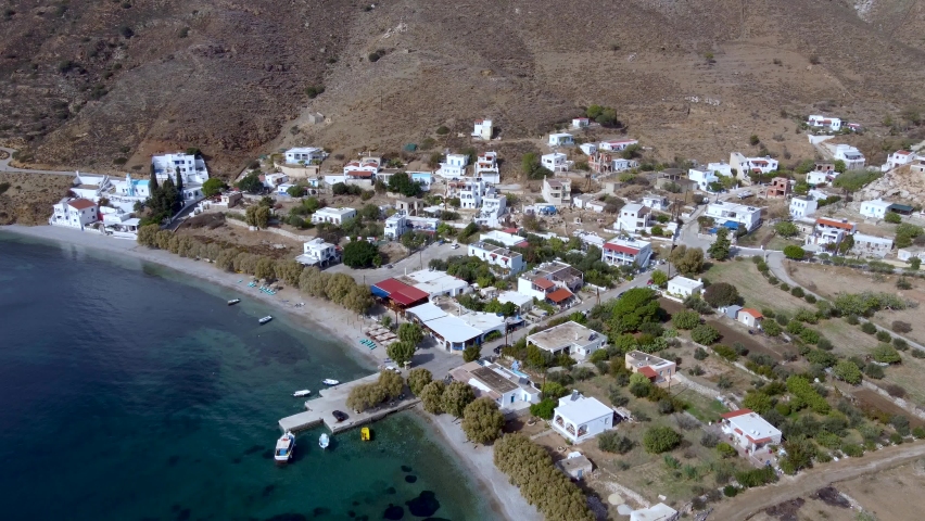 Kalymnos island, Greece - October, 2021: Attractions of the island. Backward reveal aerial shot of Emborios village and ancient  ruins on sunny day.