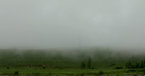 Timelapse of stratus clouds covering green mountain hill with high voltage lines during rainy day