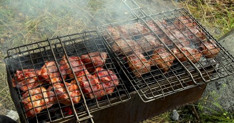 Grill grate with beef meat on a brazier with flaming charcoal. Outdoor barbecue party