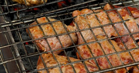 Grill grate with beef meat on a brazier with flaming charcoal. Outdoor barbecue party