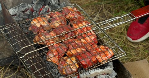 Grill grate with red meat on a brazier with flaming charcoal. Outdoor barbecue party