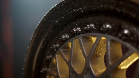 beautiful freshly painted rim from car with water drops on polished shelves and bolts. Classic wheel close up on background of garage in defocus.