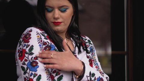 A young Ukrainian girl in an embroidered shirt walks in the park. Ukrainian national clothes embroidered women's shirt.