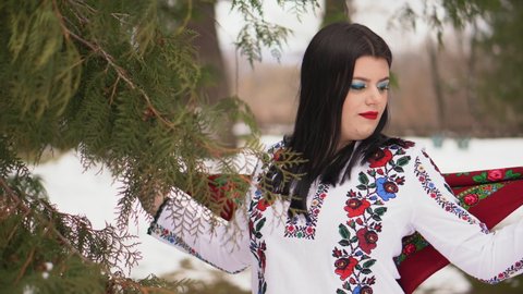 A young Ukrainian girl in an embroidered shirt walks in the park. Ukrainian national clothes embroidered women's shirt.