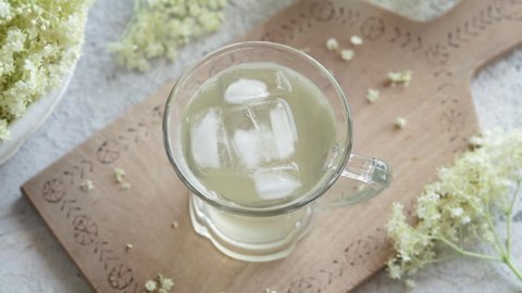 Decorating a glass of homemade herbal lemonade with fresh elder flower