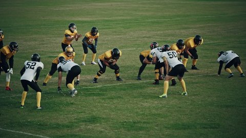 American Football Field Two Teams Compete: Successful Player Jumping Over Defense Running to Score Touchdown Points. Professional Athletes Compete for the Ball, Tackle, Fight for Victory. Wide Shot