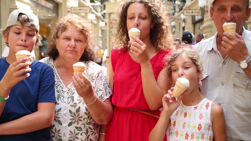 Happy family of five stand in mall ant eat sweet ice cream