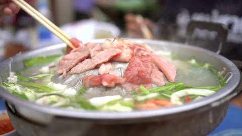4K Footage showing an unrecognizable group of people enjoy eating a traditional Thai Style pork and meat barbecue - Thai BBQ together. Thai BBQ pan called Moo Ka Ta is the popular grill in Thailand.