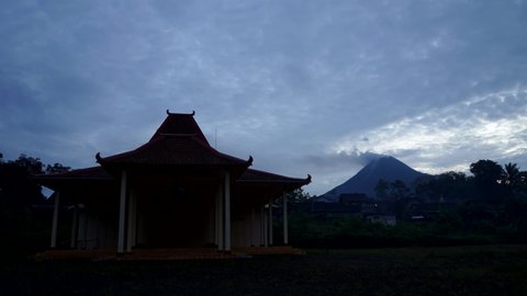 Timelapse of moving cloud over Merapi mount in Yogyakarta, Indonesia with Javanese Joglo Pendopo building in the foreground. This mountain is one of the most active volcanoes in the world.