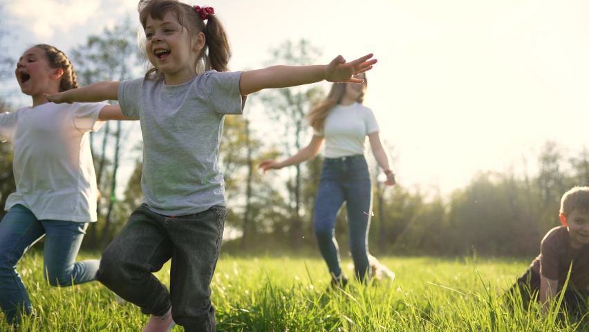 Children play in spring vacation park.Active happy group of kid run with a dog on grass in field in summer.Family in nature with pet.Child on play.Happy family concept.School in garden with dog Royalty-Free Stock Footage #1090570595