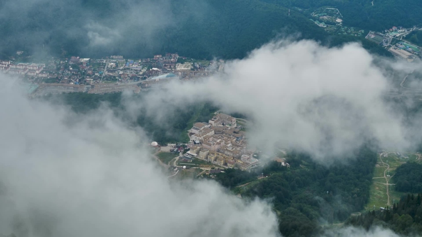 top-down view of earth and city through clouds, aerial shot