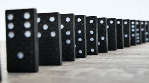 Domino effect in slow motion - falling black tiles with white dots. Dominoes falling in line effect business concept