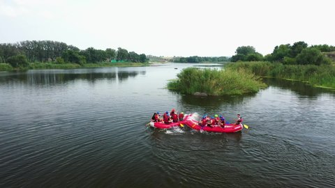 Village Myhiya, Nikolaev region, Ukraine - May 2, 2022: A group of people rafting on a river in the red rafts fully loaded with personal belongings.