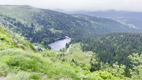 Aerial view of Lac des Truites (or Forlet) in Alsace and its surrounding forests and hills, from the top of the mountain in spring on an overcast day
