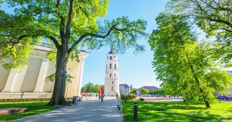 City center in Vilnius with The Cathedral Basilica, Lithuania at spring, people walking in green park, 4k panning timelapse
