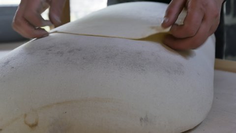 The hands of an Armenian woman are preparing the national Armenian lavash by baking in the tandoor. Spreads thin dough on a special jigging pad.