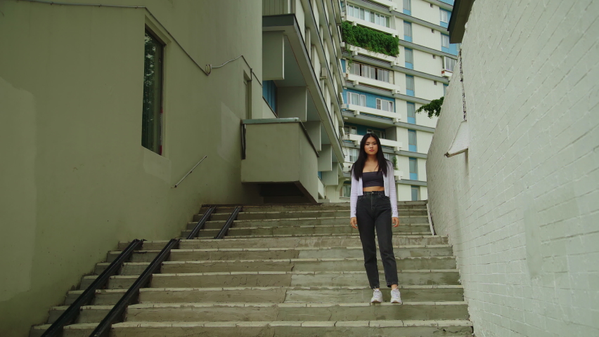 Young Asian girl stands on the stairs in the urban area Royalty-Free Stock Footage #1090578467