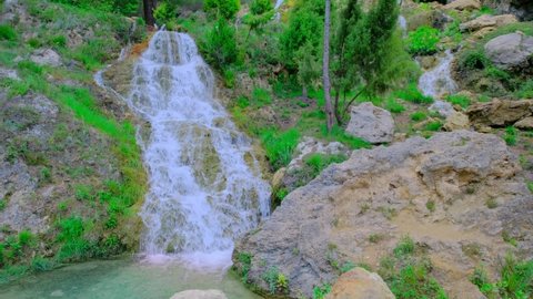 Beautiful large waterfall in a real time. Rocks, stones, green trees and bushes. Horizontal video. Turquoise water color. 