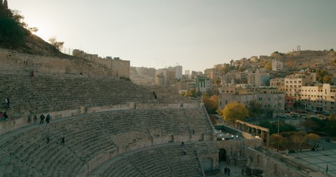 Roman Theatre - famous landmark in Amman, capital of Jordan. Typical Jordanian or Middle East Cityscape with stone Architecture and Buildings on Hills at sunset. 4K panoramic shot