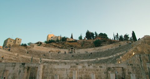 Roman Theatre - famous landmark in Amman, capital of Jordan. Typical Jordanian or Middle East Cityscape with popular Tourism and Travel attraction at sunset. 4K panoramic shot