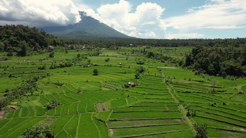 Aerial shot of Bali Volcano, Drone Shot, flying forwards, over rice fields and terraces. Cloudy sky
