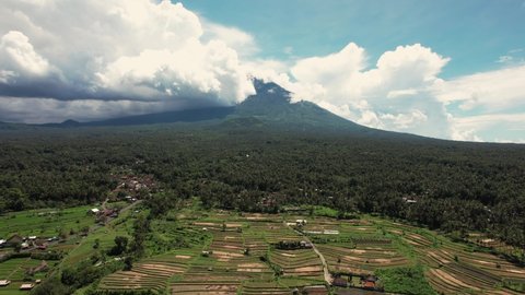 Aerial shot of Bali Volcano, Drone Shot, flying backwards over rice fields and terraces. Cloudy sky