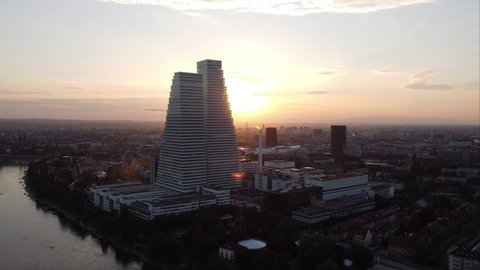 Basel, Switzerland - 19. May 2022: Aerial orbiting view of Basel city and Roche Headquarters with lens flare during sunset. 