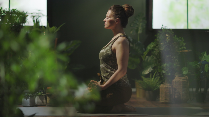 stylish housewife in the modern green house meditating.