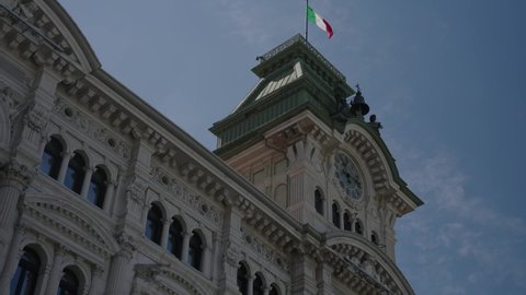 Close-up of town hall building with Italian flag on its top. Piazza Unità d'Italia. Trieste, Italy. Low angle static view.
