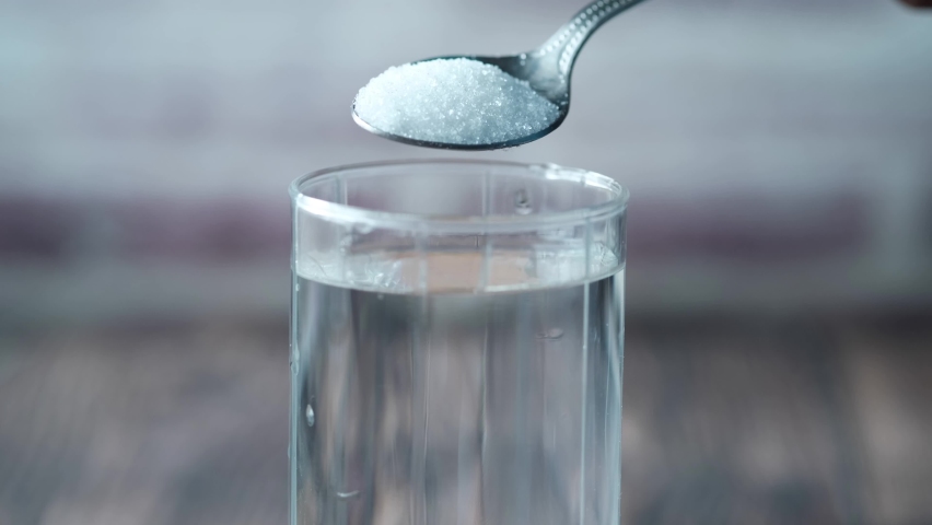 pouring white sugar in a glass of water on table  Royalty-Free Stock Footage #1090592893