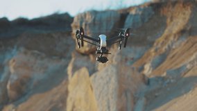 Slow motion drone flies on background rock. Modern technologies for shooting photos and videos from above. Golden hour