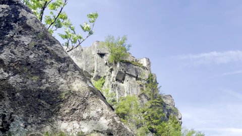 Tracking shot to the right from behind a large rock on a stone mountain cliff, at Lac Blanc in Alsace