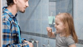 Dad and daughter brush their teeth in morning and in evening, health care, beautiful smile, white teeth. Funny home video. teaching