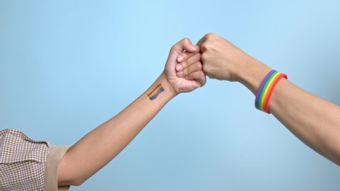 lgbt gay pride rainbow colored male hand handshake greet in protest on blue background.