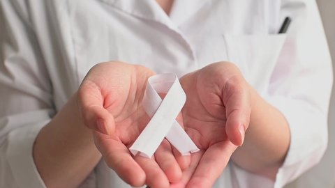 Doctor in white coat holds white ribbon. Concept lung cancer awareness. Bone cancer. FullHD