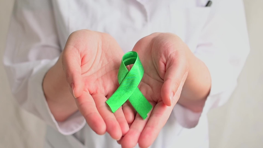 World bipolar day. Doctor in white coat holds green ribbon. Mental health awareness day, Depression, Cerebral palsy. World kidney day. FullHD Royalty-Free Stock Footage #1090604823