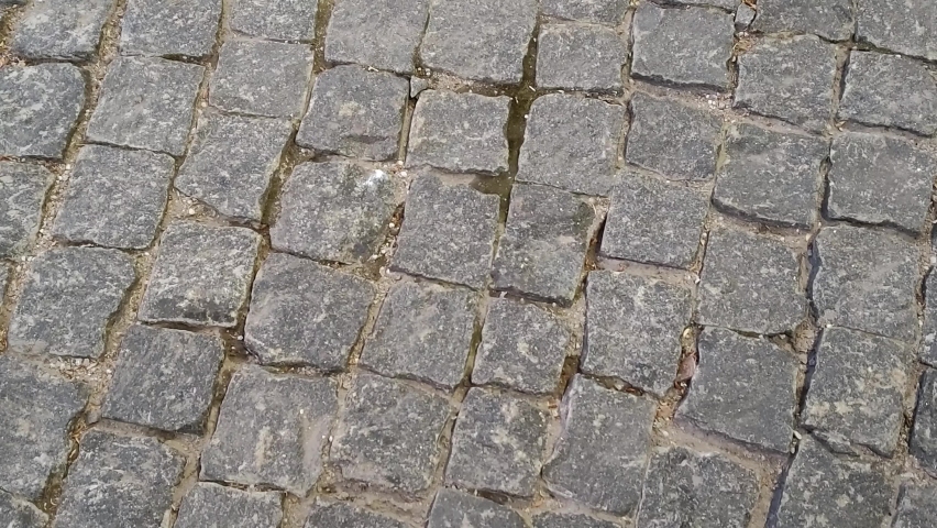 Texture of paving stones. Slow circular movement on the stones of a paved street. Sidewalk made of paving stones in a city park. 4k, footage, horizontal video, top view, close-up