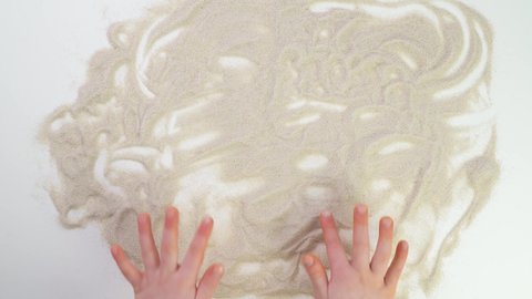 child draws sun with finger on sand. kid Game Top view paint. Caucasian hands write text in beige sand. Vacation and travel. Beach on vacation. Sand painting. Creativity from natural materials.