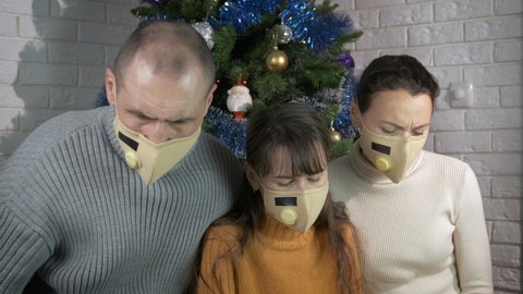Lonely Christmas with unhappy family. A lonely family celebrate in protective mask Christmas festive days in the room.