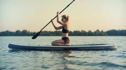 Girl Stand Up Paddle Boarding. Warm Summer Beach Vacation Holiday. Travel Paddles Paddleboard. Sup Board Journey. Young Woman Relaxing On Sup Surf Swimming. Watersport Floating On Surfboard At Sunset
